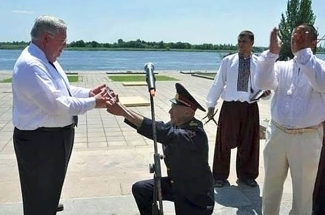 El general ucraniano de rodillas presenta un sable al ex embajador de Estados Unidos